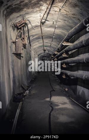 tunnel abbandonato e decadente con tubazioni Foto Stock