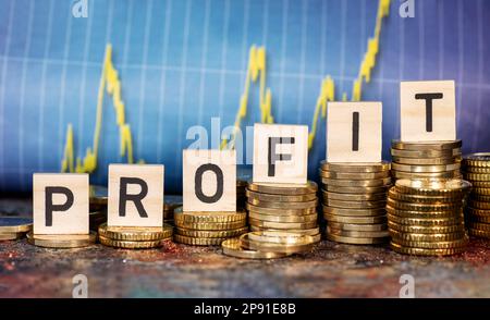 Diversi stack con monete e il termine profitto e un grafico con curva crescente. Foto Stock