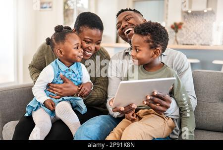 I film per famiglie sono i migliori ricordi d'infanzia. Scatto di una giovane famiglia felice utilizzando un tablet digitale sul divano a casa. Foto Stock