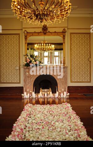 Una splendida idea di decorazione degli interni caratterizzata da un grande camino adornato con belle composizioni floreali e candele Foto Stock