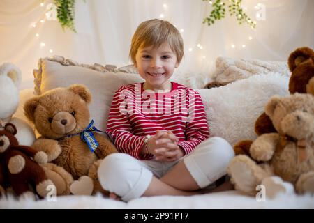 Carino ragazzo prescolare, giocando con bracciali bianchi e rossi. Martenitsa, varietà di filati bianchi e rossi, tradizione folcloristica bulgara, primavera di benvenuto Foto Stock