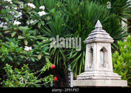 Asia outdoor tradizionale lanterna di pietra in un giardino tropicale. Marmo scolpito cantiere lampada con parco verde fogliame spazio di copia Foto Stock