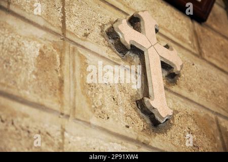 Croce decorativo su una chiesa cattolica un muro di mattoni. Simbolo del cristianesimo lo sfondo con copia spazio. La decorazione della cappella dettaglio Foto Stock