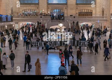 New York, New York, Stati Uniti. 9th Mar, 2023. (NUOVO) dimostrazione di Pro-immigrazione nella Grand Central Station. 09 marzo 2023, New York, New York, USA: Le persone camminano attraverso il Grand Central Terminal di Manhattan mentre i manifestanti che detengono un cartello e striscioni sono silenziosi durante una protesta a sostegno dei richiedenti asilo in mezzo al titolo 42 incertezza il 09 marzo 2023 a New York City. (Credit Image: © M10S/TheNEWS2 via ZUMA Press Wire) SOLO PER USO EDITORIALE! Non per USO commerciale! Foto Stock