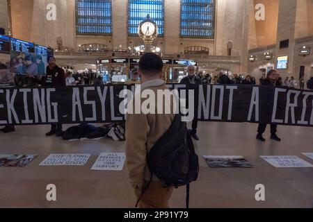 New York, New York, Stati Uniti. 9th Mar, 2023. (NUOVO) dimostrazione di Pro-immigrazione nella Grand Central Station. 09 marzo 2023, New York, New York, USA: Le persone camminano attraverso il Grand Central Terminal di Manhattan mentre i manifestanti che detengono un cartello e striscioni sono silenziosi durante una protesta a sostegno dei richiedenti asilo in mezzo al titolo 42 incertezza il 09 marzo 2023 a New York City. (Credit Image: © M10S/TheNEWS2 via ZUMA Press Wire) SOLO PER USO EDITORIALE! Non per USO commerciale! Foto Stock