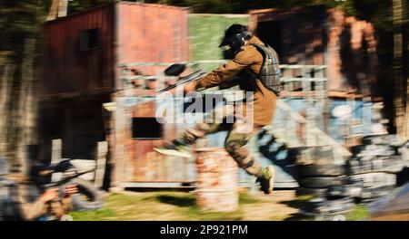 Paintball, uomo salto e mira pistola al bersaglio, tattiche militari a tiro gamma e gioco di guerra per gli sport all'aperto. Soldato con arma sul campo di battaglia Foto Stock