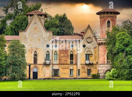 ITALIA, MIRADOLO - CIRCA AGOSTO 2020: Castello di design gotico situato in un giardino all'italiana, pieno di mistero, con luce al tramonto Foto Stock