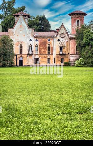 ITALIA, MIRADOLO - CIRCA AGOSTO 2020: Castello di design gotico situato in un giardino all'italiana, pieno di mistero, con luce al tramonto Foto Stock