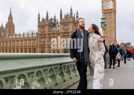 Felice coppia di giovani viaggiatori che camminano sul Westminster Bridge con Bin ben sullo sfondo Foto Stock