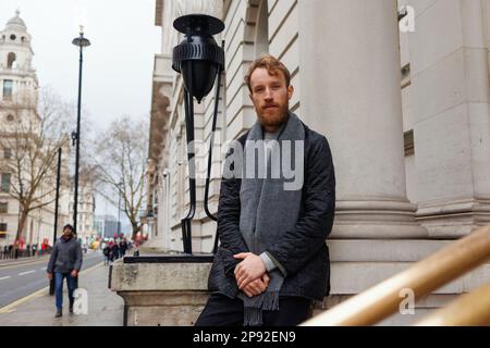 Uomo con abiti eleganti e bearded in una giacca e sciarpa posa vicino a vecchio bellissimo edificio sulle strade di Londra Foto Stock