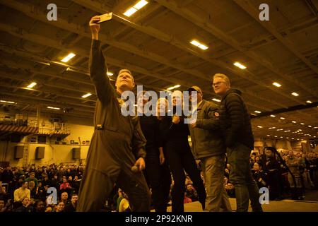 Dave Pollard, comandante a bordo della portaerei di classe Nimitz USS George H.W. Bush (CVN 77), prende un selfie sul palco con Tom Cruise, a destra, Christopher McQuarrie, al centro a destra, Hannah Waddingham, Center, Eddie Hamilton, centro a sinistra, ADM posteriore Dennis Velez, Commander Carrier Strike Group (CSG) 10 e il George H.W. Bush CSG, e i marinai durante una visita alla nave, il 2 marzo 2023, mentre le scene filmate per 'Mission: Impossible - Dead Reckoning parte due'. The George H.W. Bush Carrier Strike Group è in fase di implementazione pianificata negli Stati Uniti Naval Forces Europe area delle operazioni Foto Stock