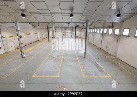 Vista dall'alto di un negozio di riparazione auto vuoto o di un parcheggio con luce naturale. Concetto di riprogettazione dello scopo dei locali. Spazio di fabbrica o di magazzino Foto Stock