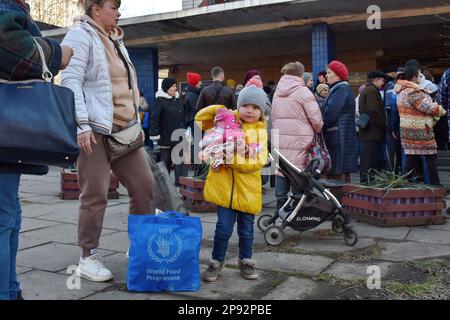 9 marzo 2023, Zaporizhzhzhia, Ucraina: Una donna con un bambino sta accanto alla borsa del PAM mentre le persone ricevono cibo in un punto di distribuzione degli aiuti umanitari a Zaporizhzhzhia. Dall'inizio dell'invasione russa, quasi un terzo degli ucraini è stato costretto a lasciare le loro case. Secondo l’Agenzia delle Nazioni Unite per i rifugiati, questa è una delle più grandi crisi di sfollamento umano al mondo. Le persone che si trovano nelle aree direttamente colpite dal conflitto hanno bisogno immediato di un sostegno salvavita, mancano cibo, energia, servizi pubblici e si trovano di fronte a un fallimento nella fornitura di servizi di base. Inoltre devono affrontare il rischio di envir Foto Stock