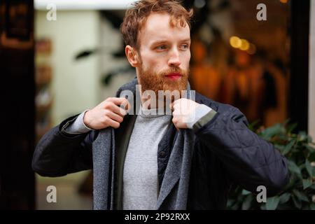 Ritratto di un uomo bearded elegantemente vestito in posa all'aperto Foto Stock
