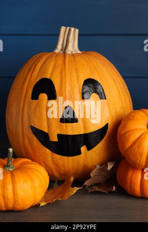 Zucche arancioni e una con la faccia spoky disegnata sul tavolo di legno. Festa di Halloween Foto Stock