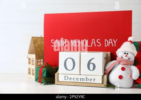 San Nicola giorno. Calendario blocco con data 06 dicembre, cartellino rosso e decorazioni festive su tavolo di legno bianco Foto Stock