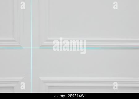 Linee trasversali della livella laser sulla parete bianca Foto Stock
