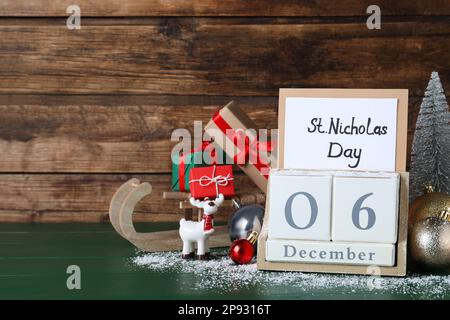 San Nicola giorno. Blocca calendario con data 06 dicembre, carta e festive decorazione su tavolo di legno verde, spazio per il testo Foto Stock