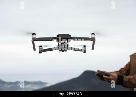 Uomo che lavora drone moderno con telecomando in montagna Foto Stock