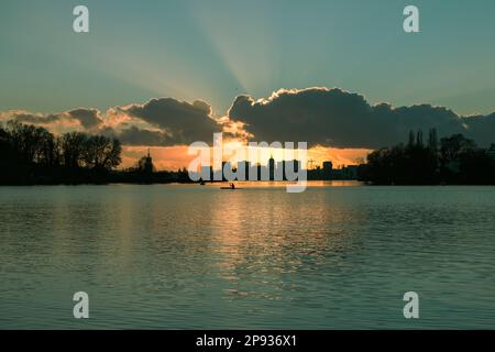 Vista sul profondo lago di Potsdam fino al tramonto con canoista e la silhouette della città di Potsdam sullo sfondo Foto Stock