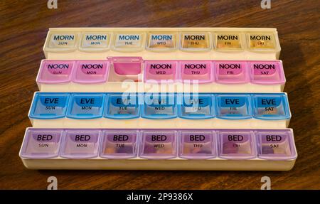 Un organizzatore settimanale parzialmente riempito di pillola con quattro recipienti per ogni giorno Foto Stock