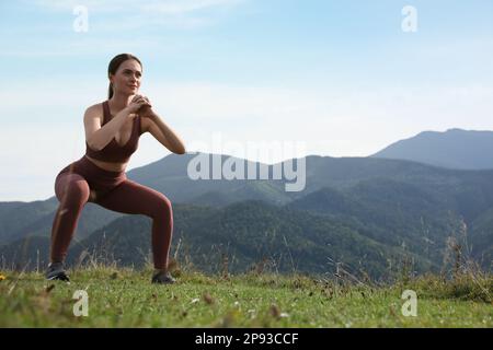 Giovane donna che fa esercizio mattutino in montagna, spazio per il testo Foto Stock