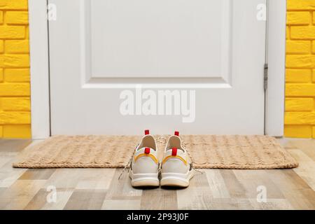 Scarpe e tappetino vicino alla porta nel corridoio Foto Stock