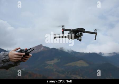 Donna che lavora drone moderno con telecomando in montagna, primo piano Foto Stock