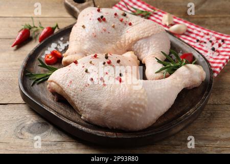 Quarti di coscia di pollo crudo e ingredienti su tavolo di legno Foto Stock