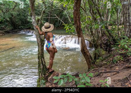 Nord America, Caraibi, grandi Antille, Isola di Hispaniola, Repubblica Dominicana, Provincia di Monte Plata, Bayaguana, attraente donna appoggiata ad un albero sul fiume Foto Stock