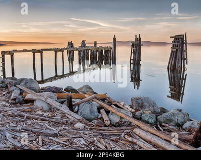 Il sole sta per arrivare sopra l'orizzonte sopra un vecchio molo di pescatori sull'isola di San Juan. Foto Stock