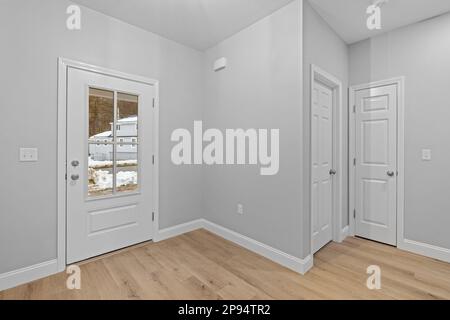 Interni dal design moderno e minimalista con una camera bianca con porte bianche e pavimento in legno Foto Stock