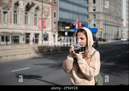 Giovane ragazza turistica nella città americana di Chicago che scatta foto con una vecchia fotocamera a rulli classica Foto Stock