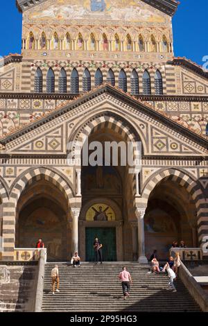 Turisti a pochi passi dal Duomo di Sant'Andrea. Amalfi, Salerno, Italia Costiera Amalfitana. Iniziata nei secoli 9th e 10th, la cattedrale è stata aggiunta e ridecorata più volte, sovrapponendo elementi arabo-normanni, gotici, rinascimentali, barocchi, E infine una nuova facciata Normanno-Arabo-Bizantina del 19th° secolo. Foto Stock