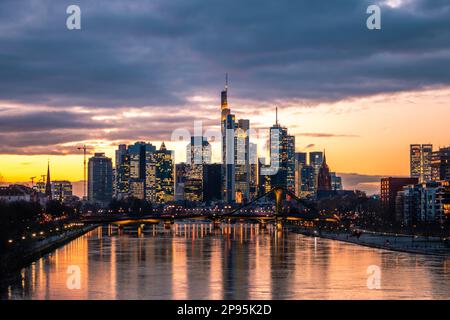 Vista sul fiume meno fino ai grattacieli della città di Francoforte sul meno al tramonto, skyline illuminato dalla luce posteriore Foto Stock
