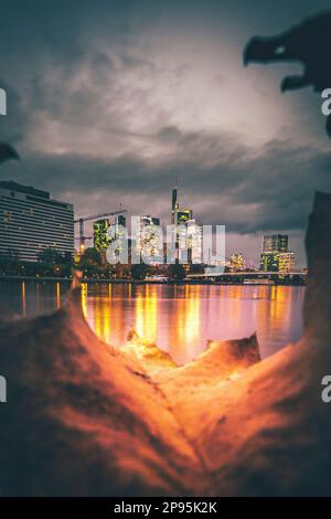 Vista sul fiume meno fino ai grattacieli della città di Francoforte sul meno al tramonto, skyline illuminato dalla luce posteriore Foto Stock