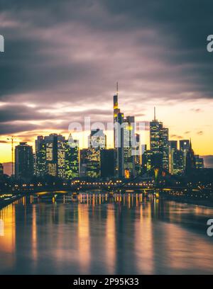 Vista sul fiume meno fino ai grattacieli della città di Francoforte sul meno al tramonto, skyline illuminato dalla luce posteriore Foto Stock