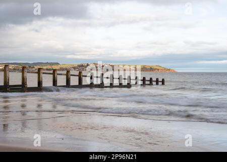 Foto paesaggistica di un groyne in mare alla riserva naturale di Dawlish Warren con Exmouth sullo sfondo Foto Stock