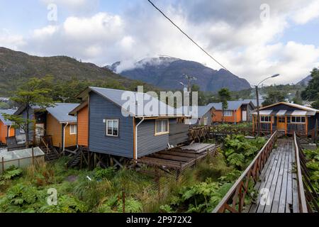 Piccole case colorate e piante nalca lungo i sentieri in legno di Tortel, Patagonia, Cile Foto Stock