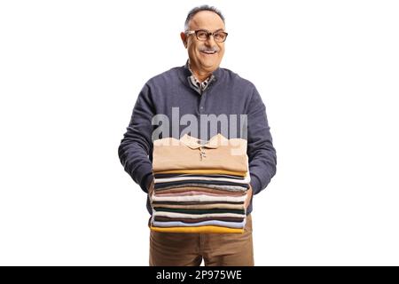 Uomo maturo allegro che tiene un mucchio di vestiti piegati e sorridente alla macchina fotografica isolata su uno sfondo bianco Foto Stock