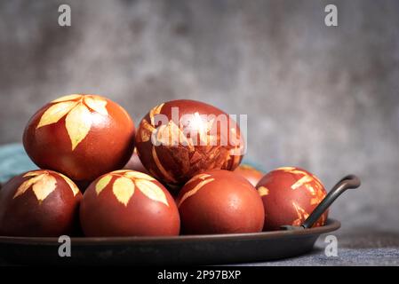 Primo piano delle uova di Pasqua tinte con bucce di cipolla con un motivo di erbe fresche in un cestino di vimini Foto Stock