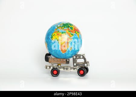 Globo su una piccola auto per bambini su sfondo bianco, trasporto internazionale, logistica e consegna Foto Stock