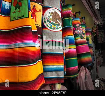 Diversi grembiuli di stoffa colorata in esposizione per la vendita in un negozio di bazar turistico con oggetti tradizionali provenienti dal Messico. Foto Stock