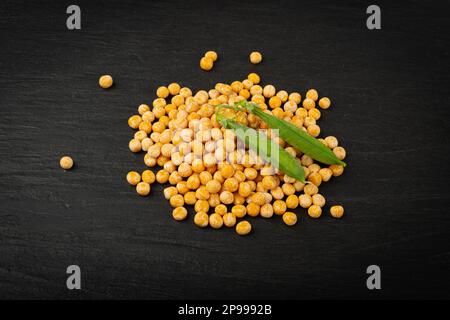 Piselli gialli secchi su fondo nero, pile di piselli interi, legume grezzo, fonte proteica, cibo vegano sano, Piselli gialli secchi sparsi su sfondo bianco Foto Stock