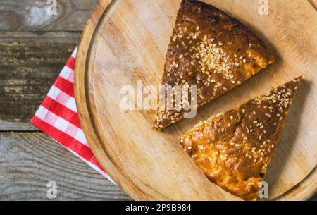 Torta fatta in casa con semi di sesamo e crosta rudosa su sfondo di legno. cottura fatta in casa Foto Stock