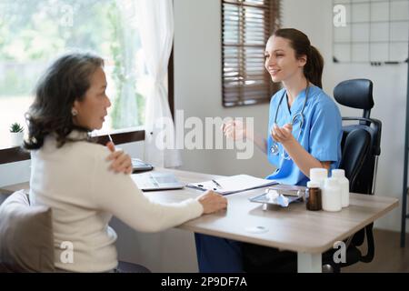 Ritratto di una dottoressa discutere con un paziente con dolore alle spalle. Foto Stock