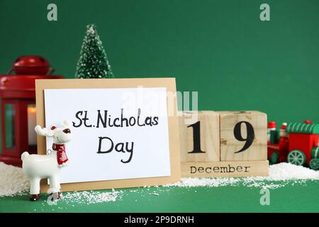 19 dicembre giorno di San Nicola. Calendario blocco, carta e decorazioni festive su sfondo verde Foto Stock