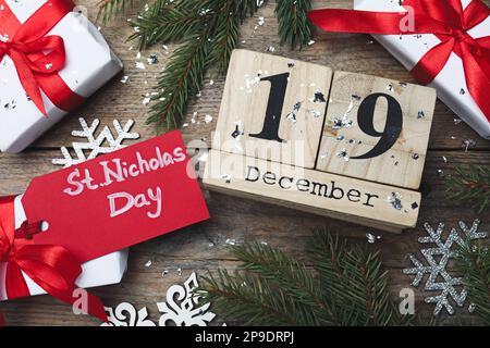 San Nicola giorno. Calendario blocco con data 19 dicembre, decorazioni festive e scatole regalo su tavolo di legno, piatto Foto Stock