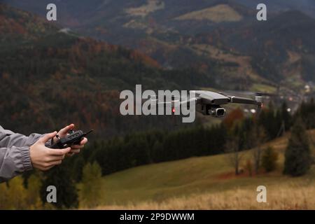 Donna che lavora drone moderno con telecomando in montagna, primo piano Foto Stock