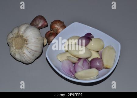 Alcune cipolle e garlics in una ciotola piccola dopo il peeling della loro pelle Foto Stock